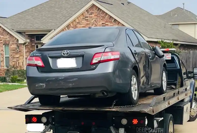 Toyota Camry gris chocado subido a una grúa en The Woodlands, TX para venta como carro chatarra con remolque gratis.
