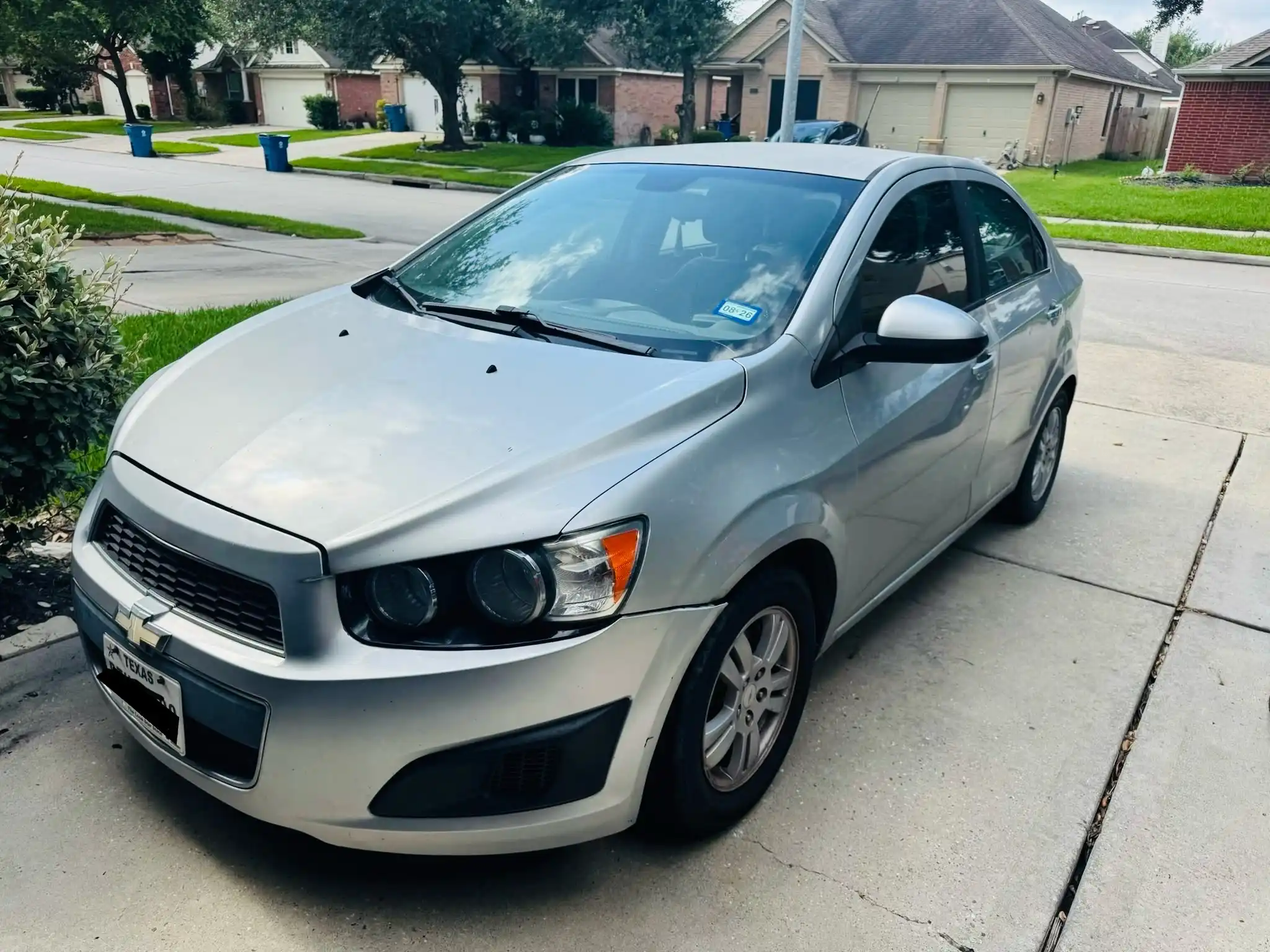 Silver Chevrolet sedan parked in a Houston driveway before being sold as a broken-down or unwanted vehicle.