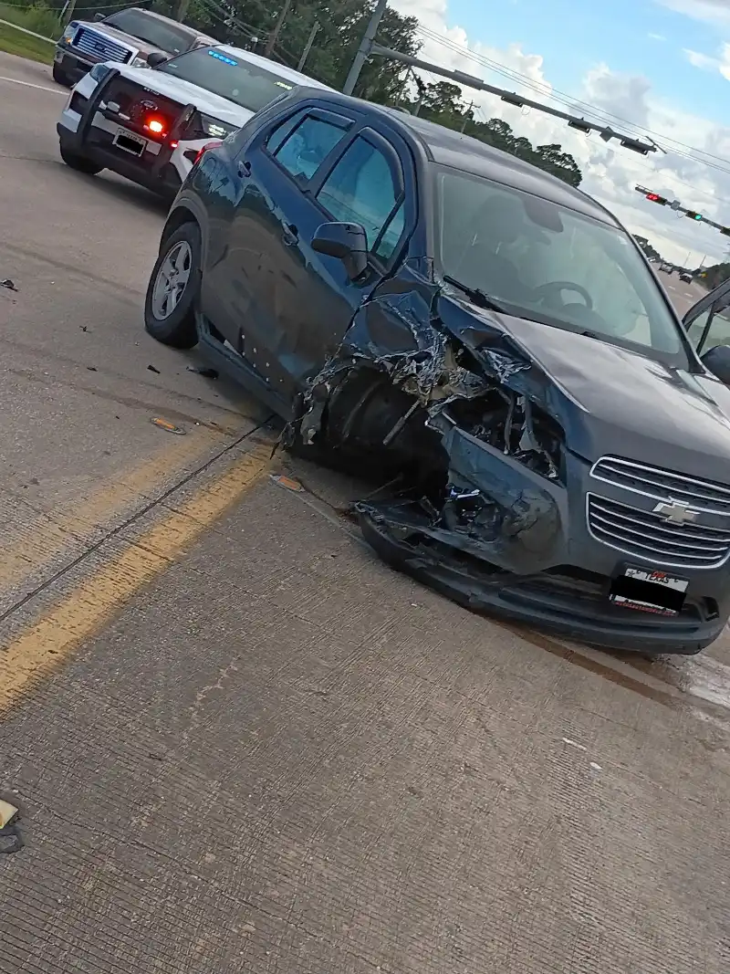 Gray Chevrolet Sonic with severe front-side collision damage on a road.